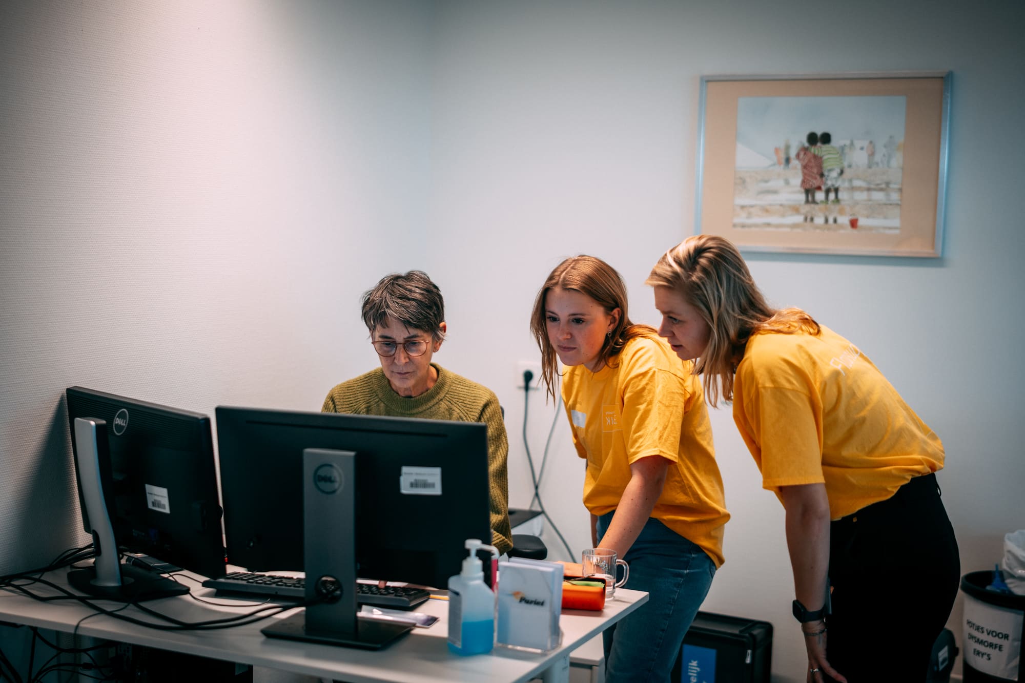 Twee floorsupporters van Young KINASE kijken tijdens een go-live mee bij een medewerker achter de computer