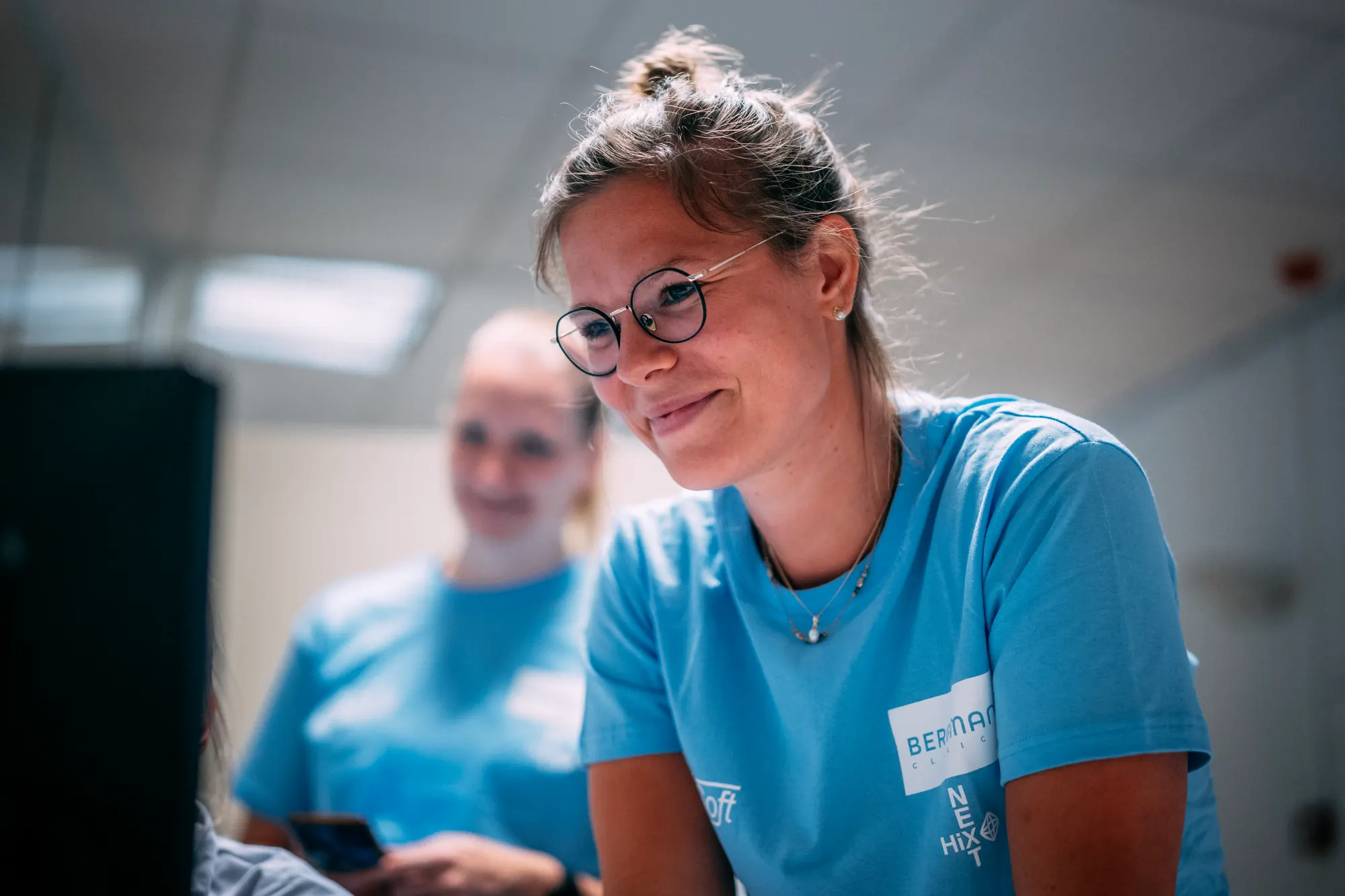 Twee young professionals van Young KINASE kijken samen naar een beeldscherm